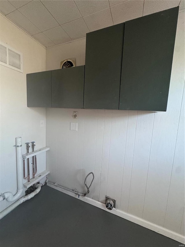 clothes washing area featuring visible vents and cabinet space