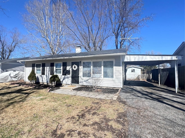 single story home featuring a chimney, aphalt driveway, fence, a front lawn, and a carport