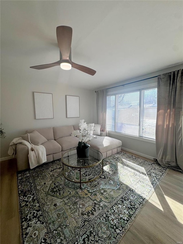 living room featuring ceiling fan, baseboards, and wood finished floors