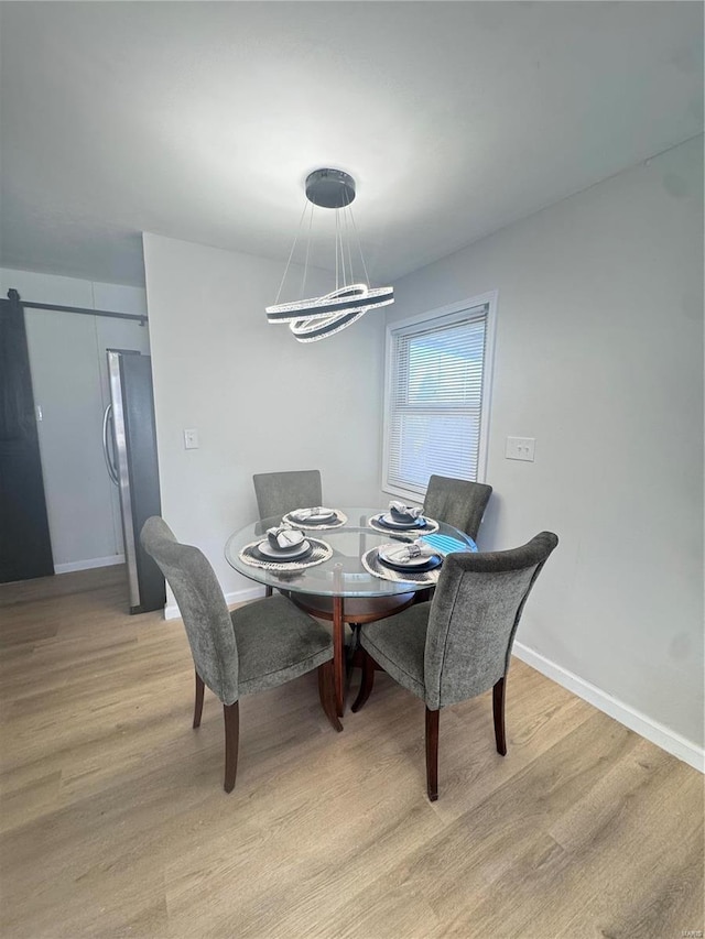 dining area with light wood finished floors, baseboards, and a notable chandelier