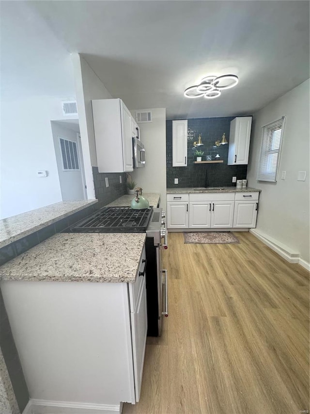 kitchen featuring tasteful backsplash, visible vents, appliances with stainless steel finishes, light wood-style floors, and a sink