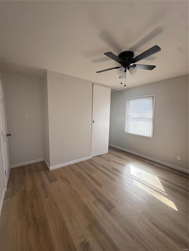 spare room with wood finished floors, a ceiling fan, and baseboards