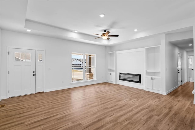 unfurnished living room featuring light wood-type flooring, a glass covered fireplace, and recessed lighting