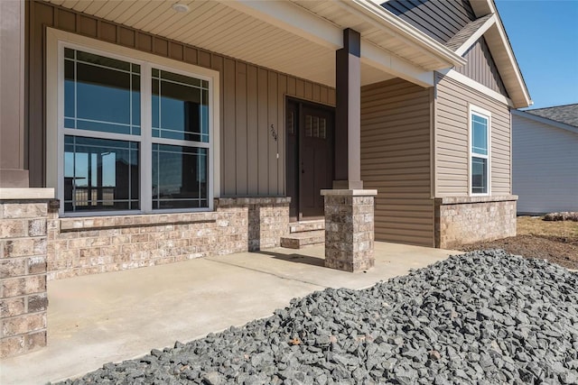 entrance to property featuring board and batten siding, stone siding, and covered porch