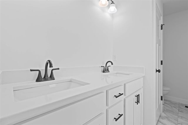 full bathroom with marble finish floor, a sink, toilet, and double vanity