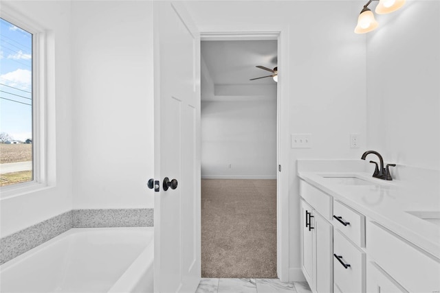 bathroom with marble finish floor, a garden tub, double vanity, ceiling fan, and a sink