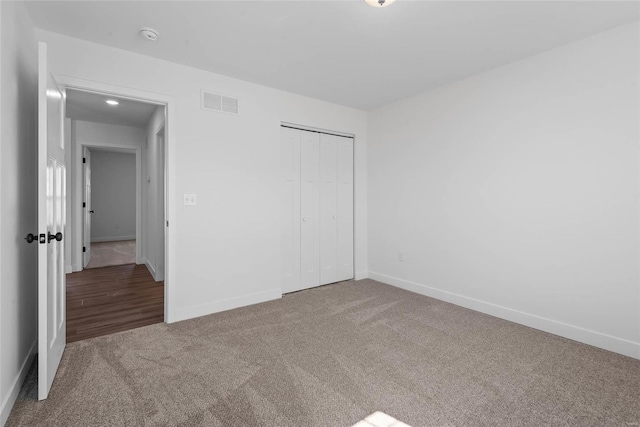 unfurnished bedroom featuring a closet, carpet, visible vents, and baseboards