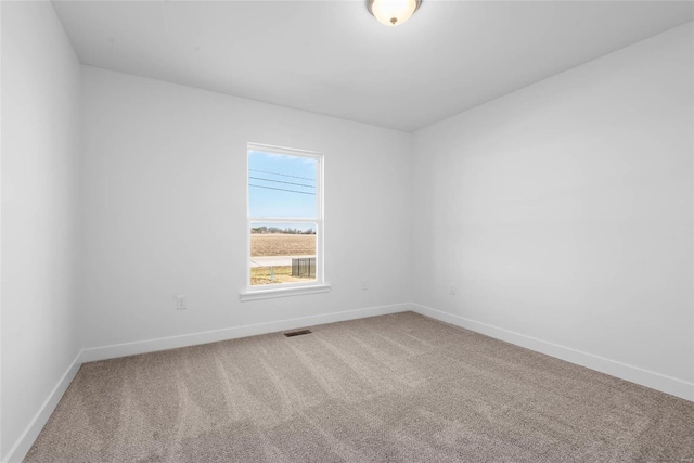 spare room featuring carpet, visible vents, and baseboards