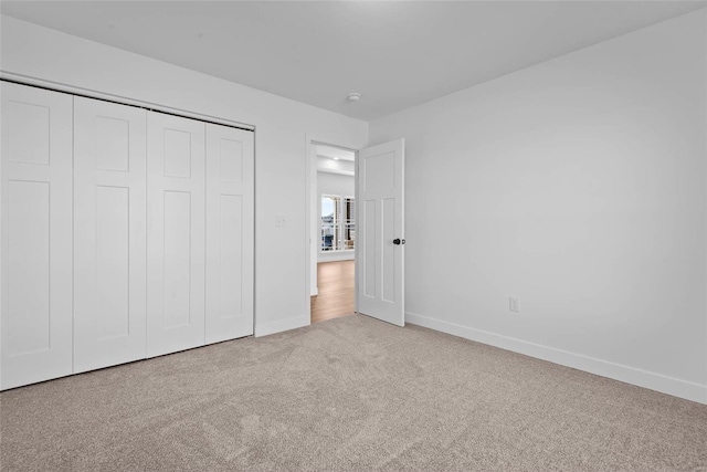 unfurnished bedroom with a closet, carpet, and baseboards