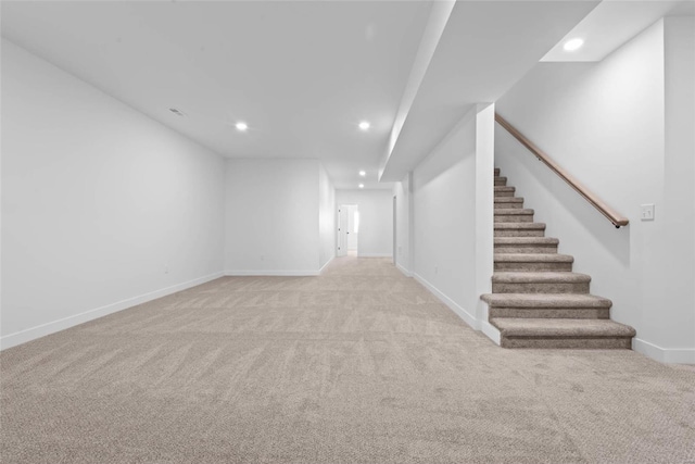 unfurnished living room featuring recessed lighting, light colored carpet, baseboards, and stairs