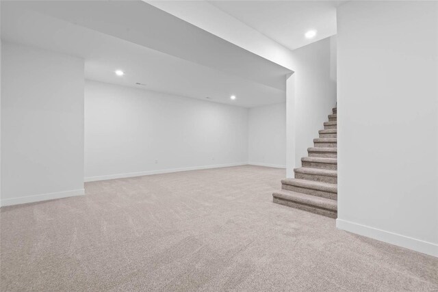 finished below grade area with carpet floors, stairway, baseboards, and recessed lighting