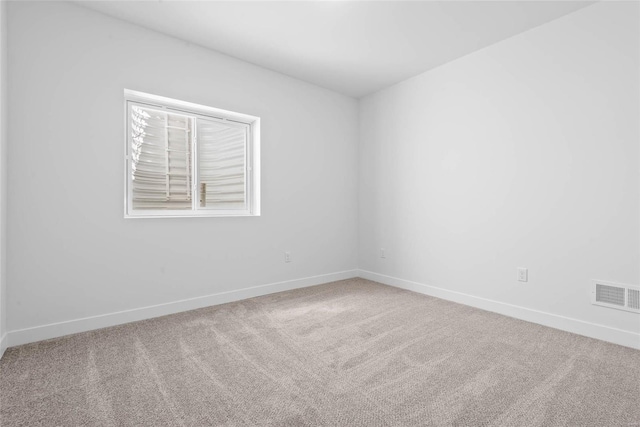 unfurnished room with carpet floors, visible vents, and baseboards