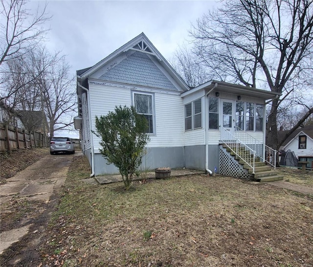 exterior space with stairs, driveway, fence, and a sunroom