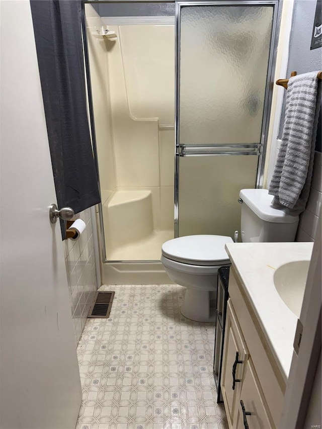 bathroom with toilet, a shower stall, visible vents, and vanity