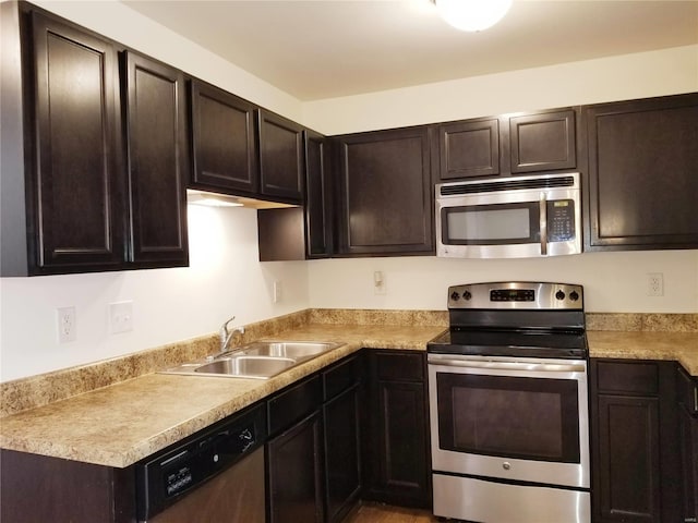 kitchen featuring light countertops, appliances with stainless steel finishes, a sink, and dark brown cabinetry