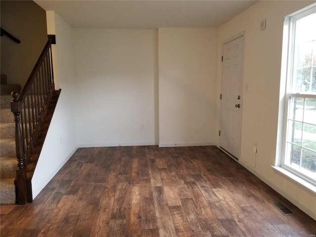 unfurnished room featuring stairs, wood finished floors, visible vents, and baseboards