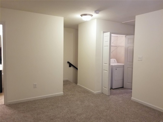 empty room featuring baseboards, washer / dryer, and light colored carpet