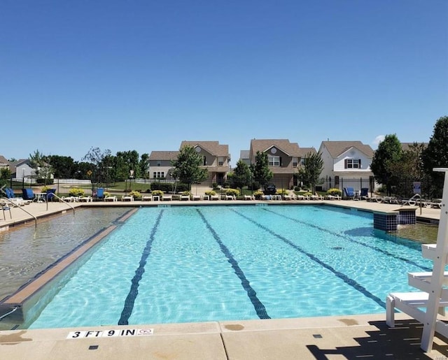 community pool featuring a patio area, fence, and a residential view