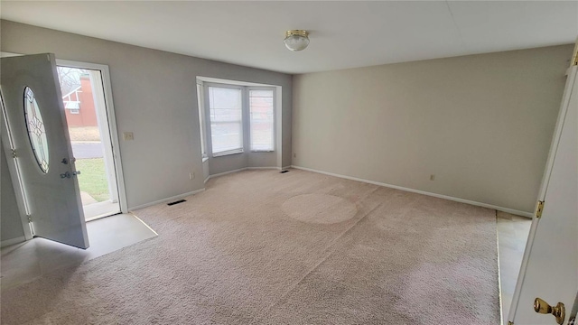 interior space with a wealth of natural light, light colored carpet, visible vents, and baseboards