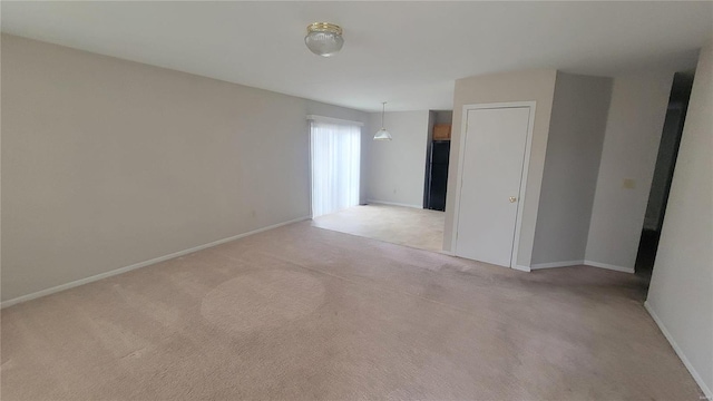 spare room with light carpet and baseboards