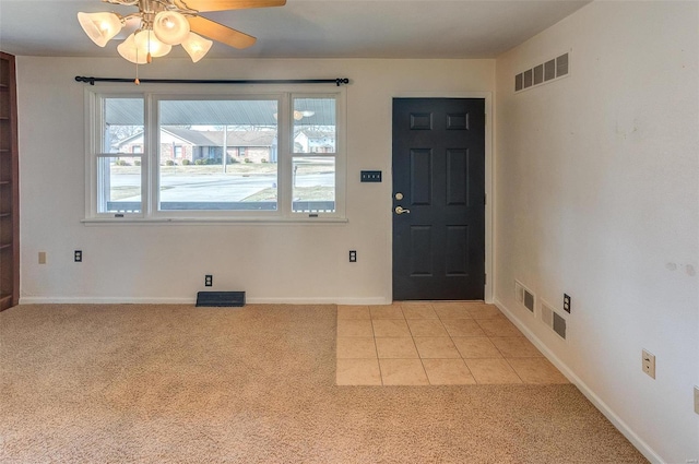 foyer entrance with baseboards, light tile patterned flooring, visible vents, and light colored carpet