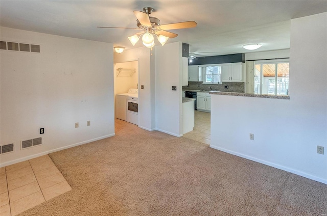 unfurnished living room featuring light tile patterned flooring, light colored carpet, a sink, visible vents, and washer / dryer