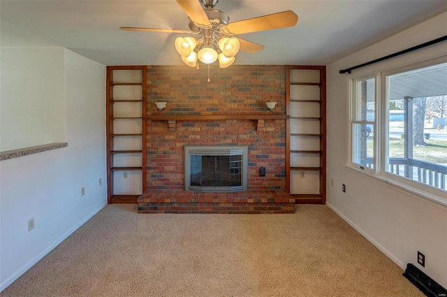 unfurnished living room with a brick fireplace, a ceiling fan, baseboards, and carpet flooring