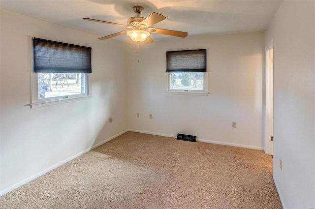 carpeted empty room with baseboards, a wealth of natural light, and a ceiling fan