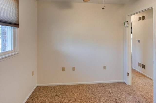 carpeted spare room featuring ceiling fan, visible vents, and baseboards