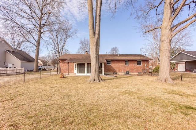 back of property with a yard, fence, and brick siding