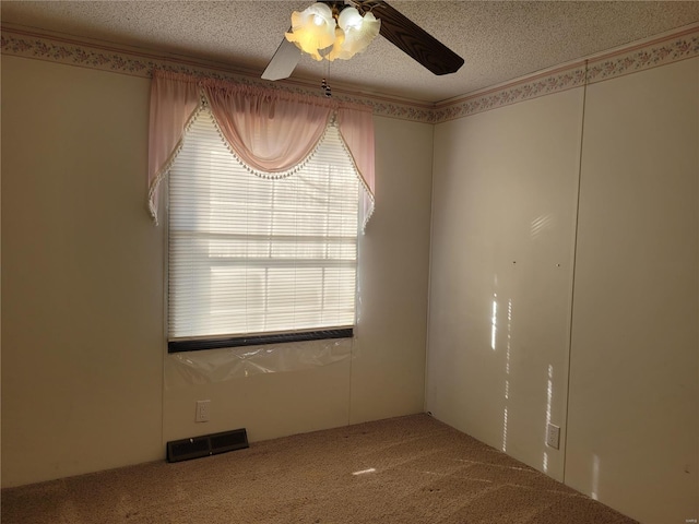 carpeted spare room with crown molding, visible vents, ceiling fan, and a textured ceiling