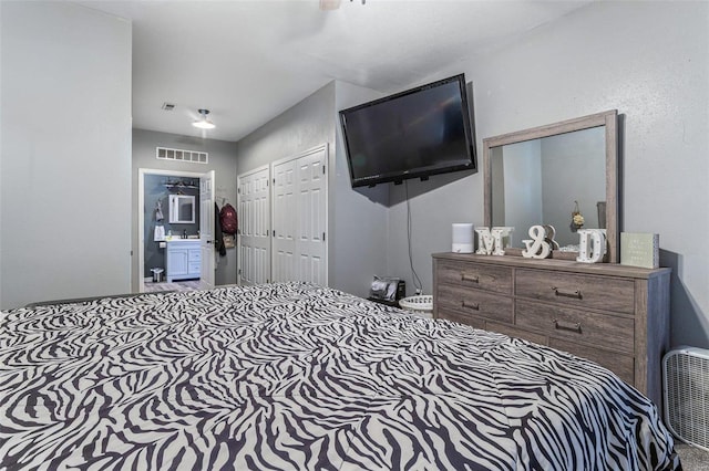 bedroom featuring ensuite bath, visible vents, and two closets