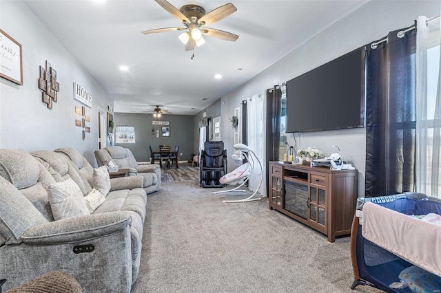 living area featuring light colored carpet and ceiling fan