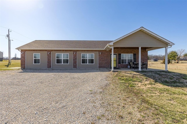 single story home featuring a patio, brick siding, roof with shingles, and a front lawn