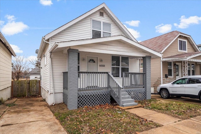 bungalow-style home featuring covered porch and fence