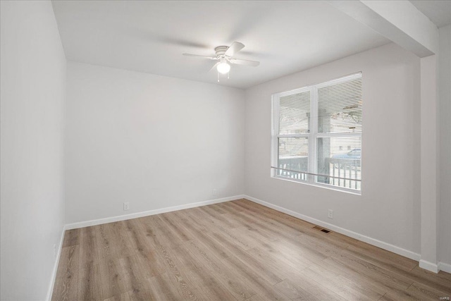 unfurnished room with a ceiling fan, visible vents, baseboards, and wood finished floors