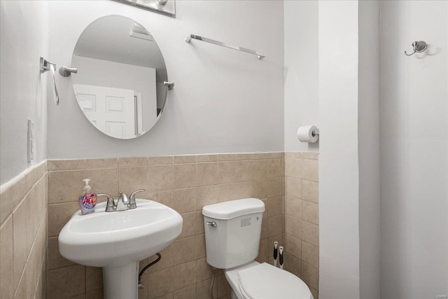 bathroom with a wainscoted wall, tile walls, and toilet