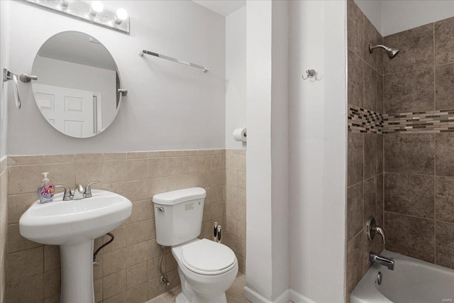 bathroom featuring toilet, a wainscoted wall, tile walls, and bathing tub / shower combination