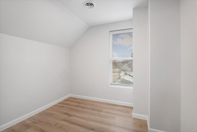 bonus room featuring light wood-style floors, baseboards, visible vents, and vaulted ceiling