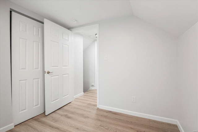 interior space featuring vaulted ceiling, light wood finished floors, and baseboards