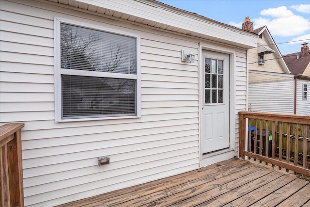 view of exterior entry with a chimney and a wooden deck