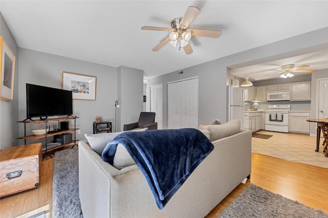 living room with visible vents, ceiling fan, and light wood finished floors