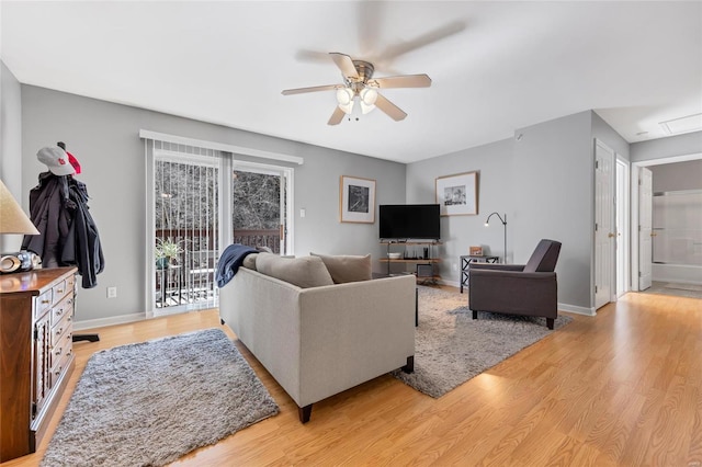 living room with baseboards, ceiling fan, and light wood finished floors