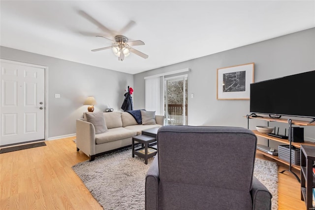 living area with a ceiling fan, light wood-style flooring, and baseboards