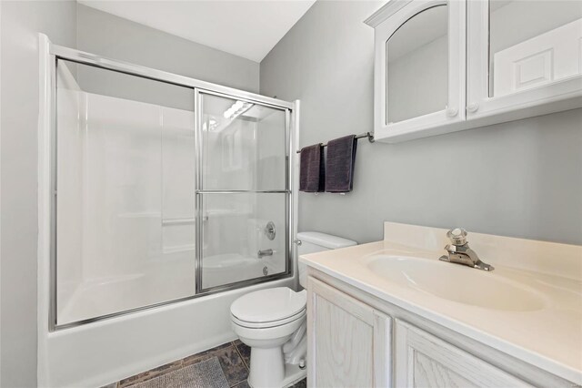 full bathroom featuring vanity, toilet, and bath / shower combo with glass door