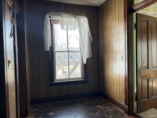 unfurnished room with wood-type flooring and wooden walls