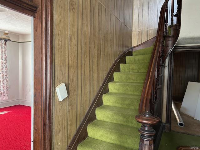 stairway with carpet floors and wooden walls