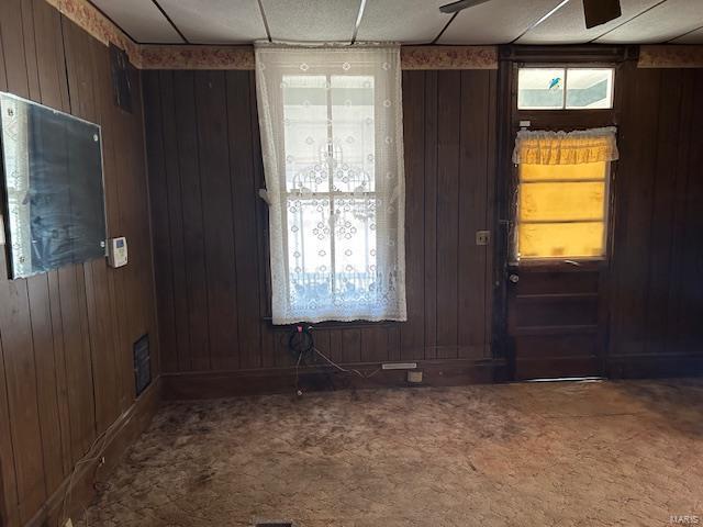 unfurnished room featuring carpet, visible vents, and wooden walls