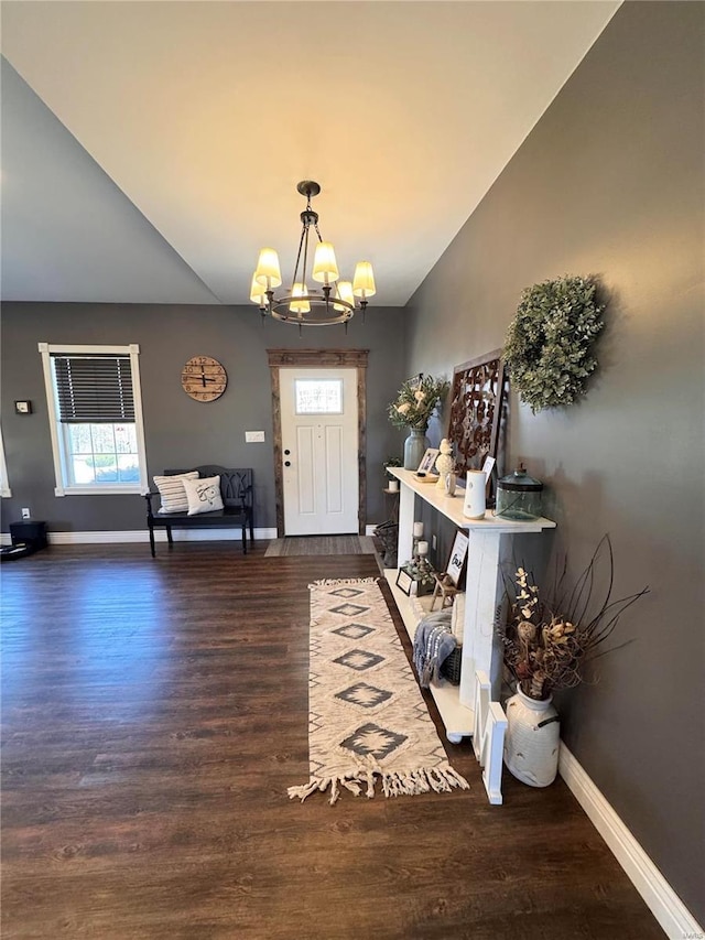 entrance foyer featuring baseboards, wood finished floors, lofted ceiling, and a notable chandelier