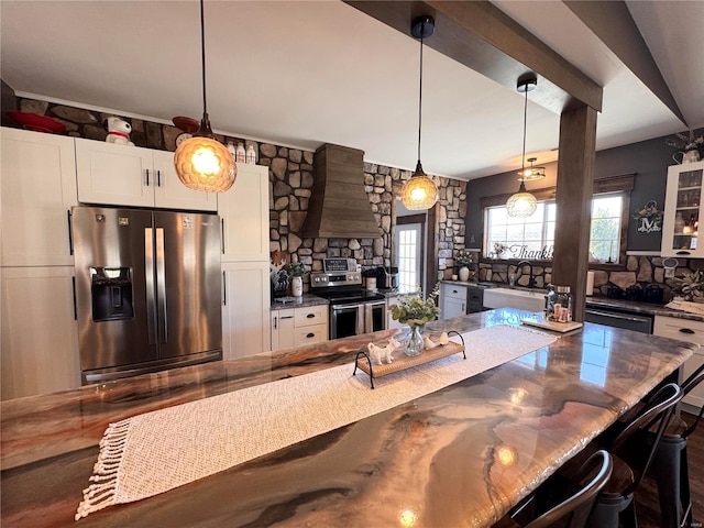 kitchen featuring premium range hood, a sink, white cabinetry, appliances with stainless steel finishes, and decorative light fixtures